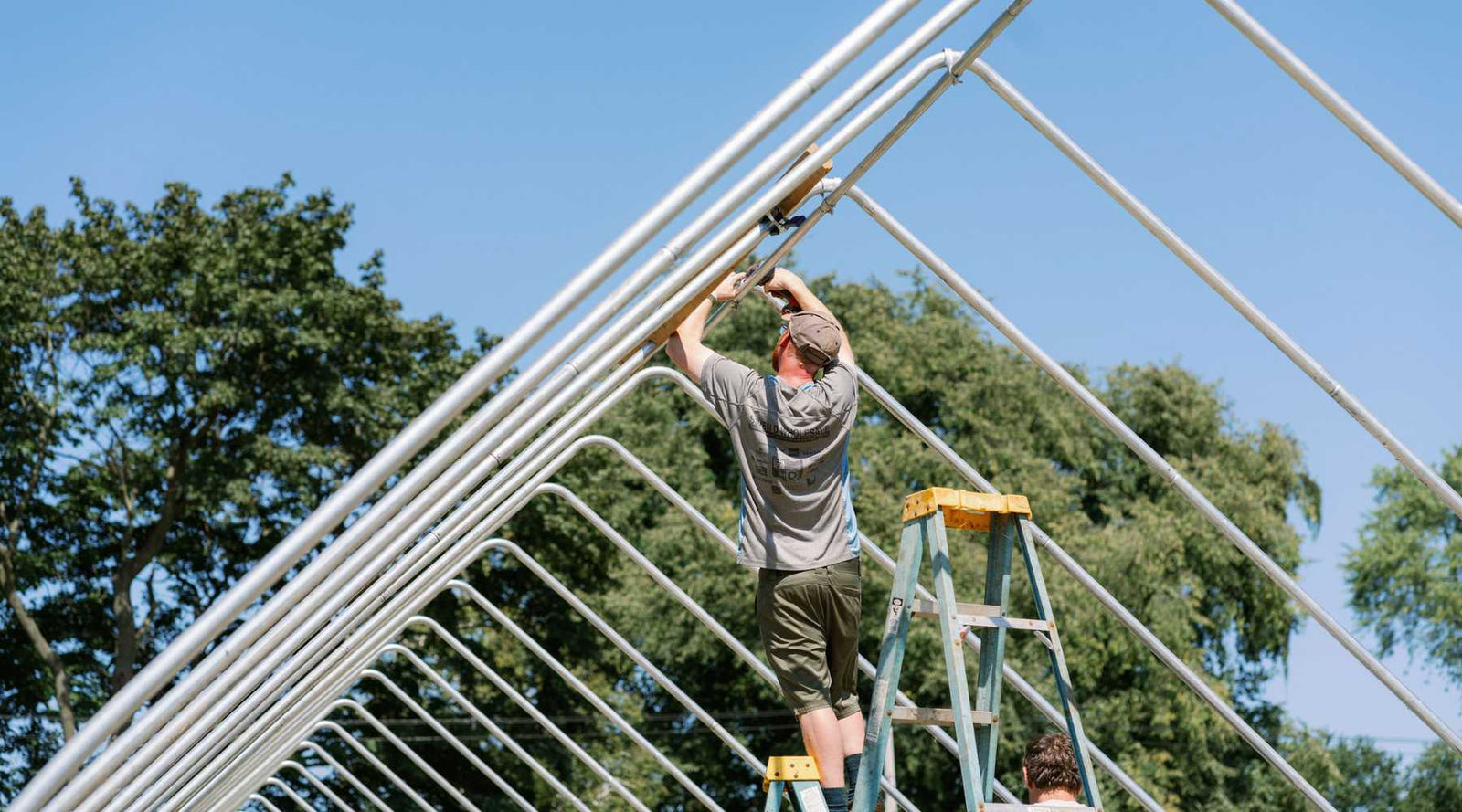 Workers adding purlins to a gothic high tunnel