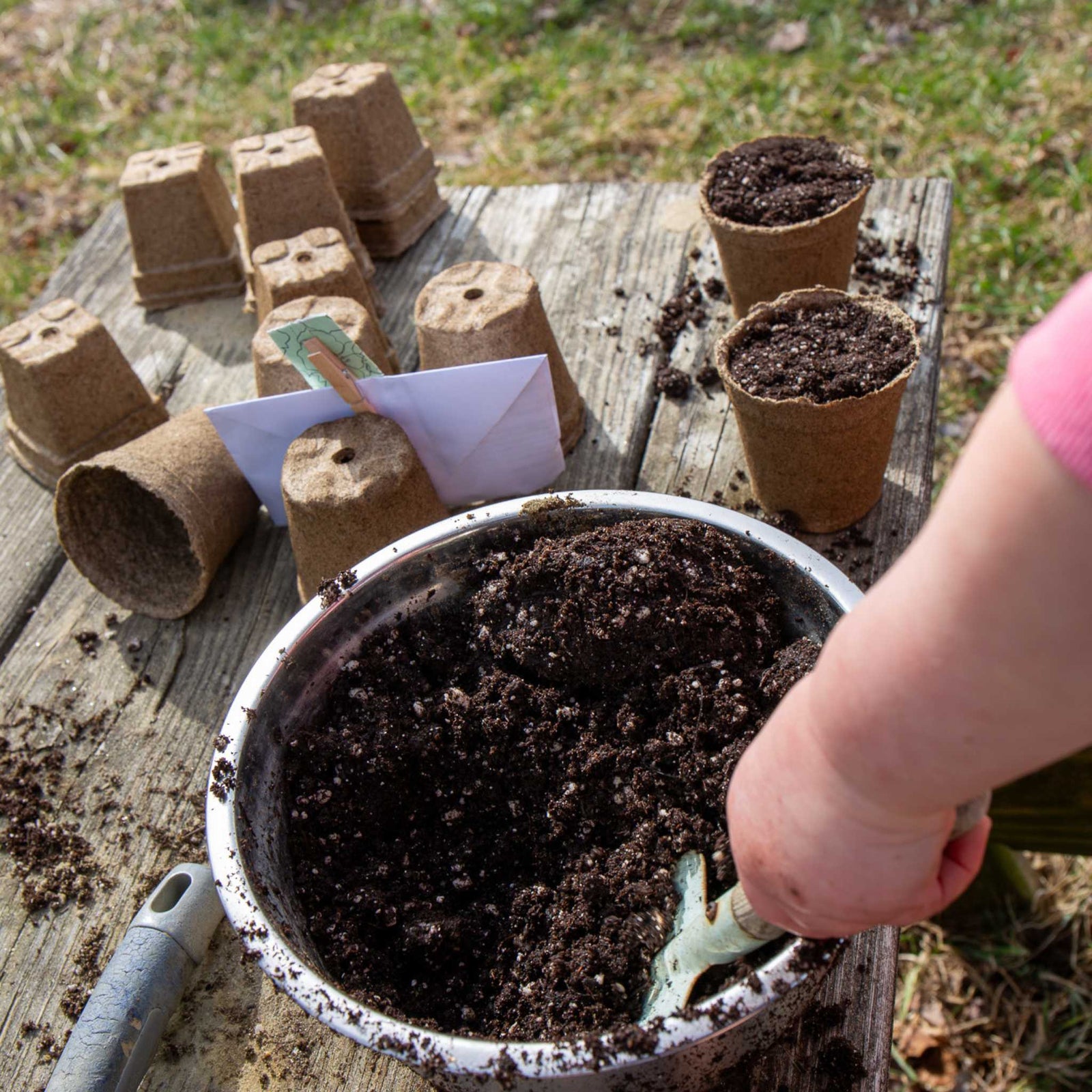 Child filling 3 in round cowpots with soil