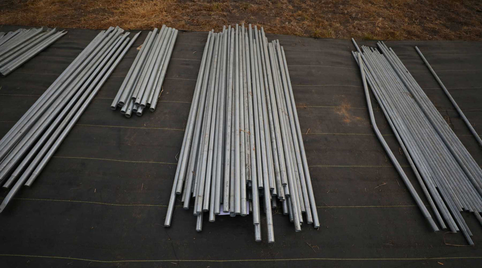 All greenhouse parts laid out on the ground in organized piles.