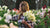 A field of Sweet Pea flowers in white, cream, pink, and red. Jessica from Sierra Flower Farm is harvesting a large bundle of creamy green tinted flowers.  