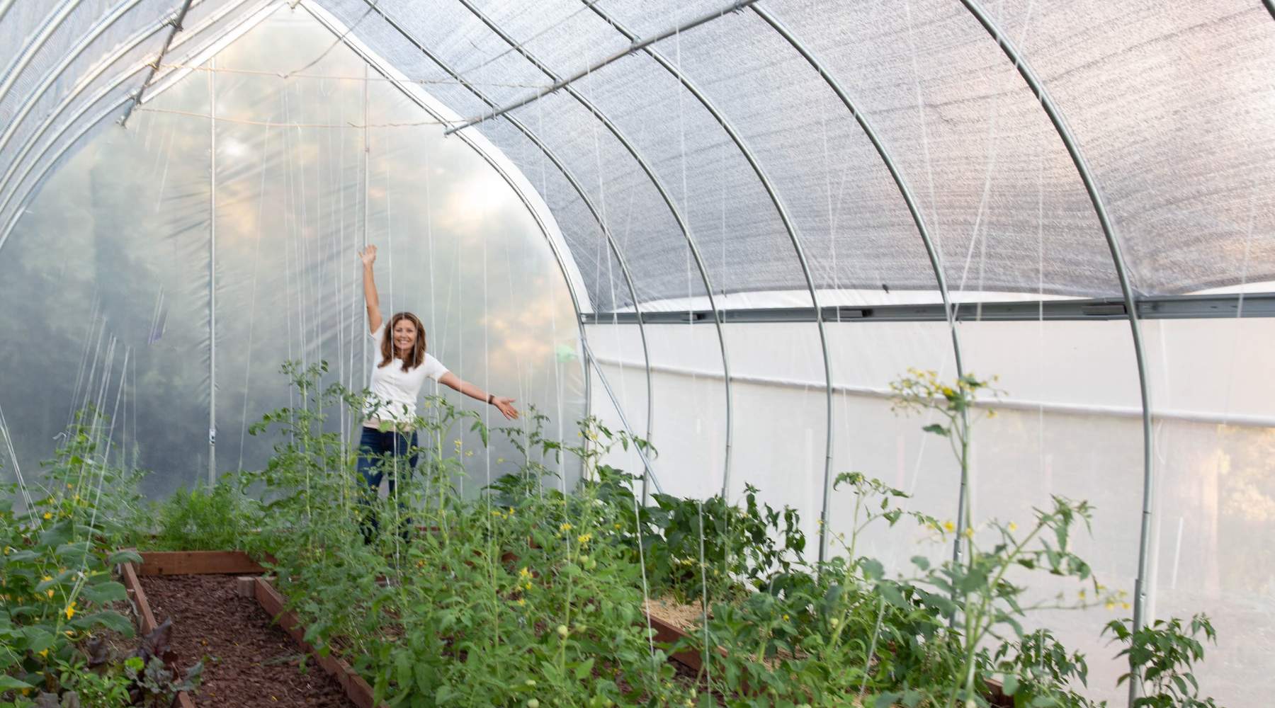 Side view of a gothic greenhouse with shade cloth over the top.