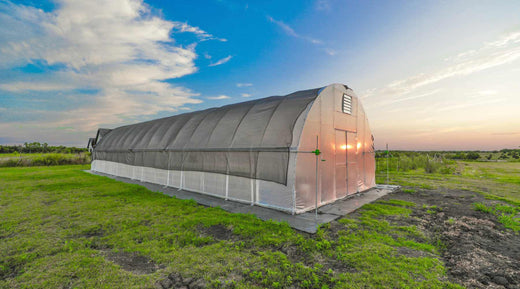 A Bootstrap Farmer round high tunnel in a field at sunset with black shade cloth. 