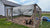 Large backyard chicken run with reflective shade cloth wrapped partially over the top and side of the run fencing. Small flock of various chicken breeds standing by fencing inside the run.