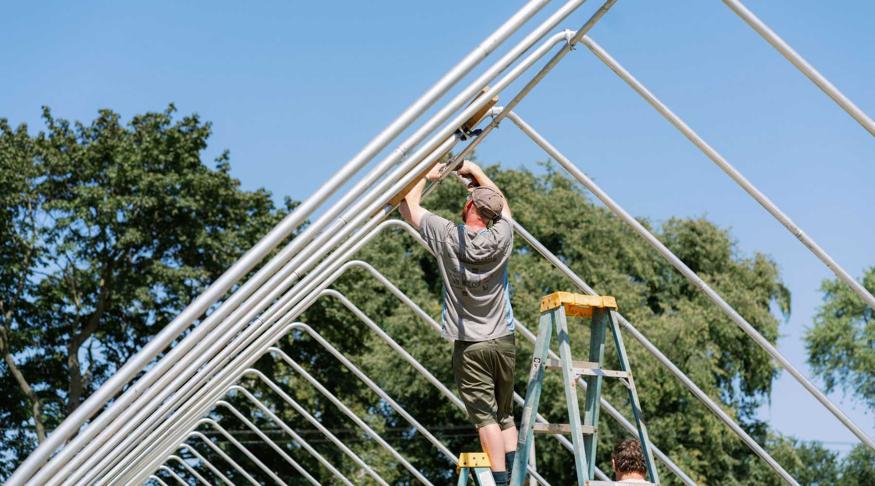 Workers adding purlins to a gothic high tunnel