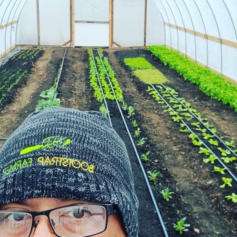 Tracy Lutz in his diy high tunnel with lettuce growing on drip irrigation