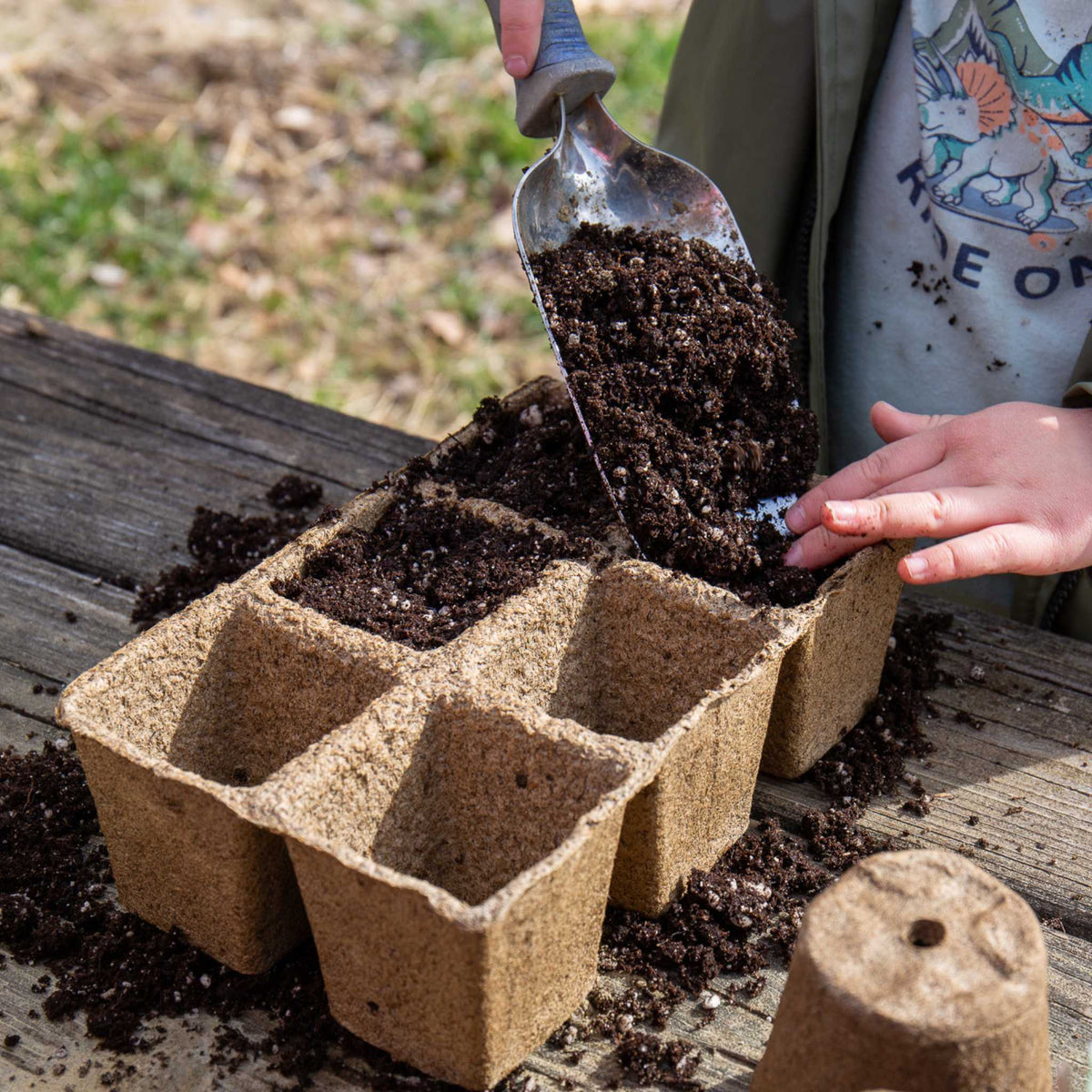 Child filling 6 cell cowpot with soil