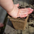 child compressing dirt into 3 in square cowpot