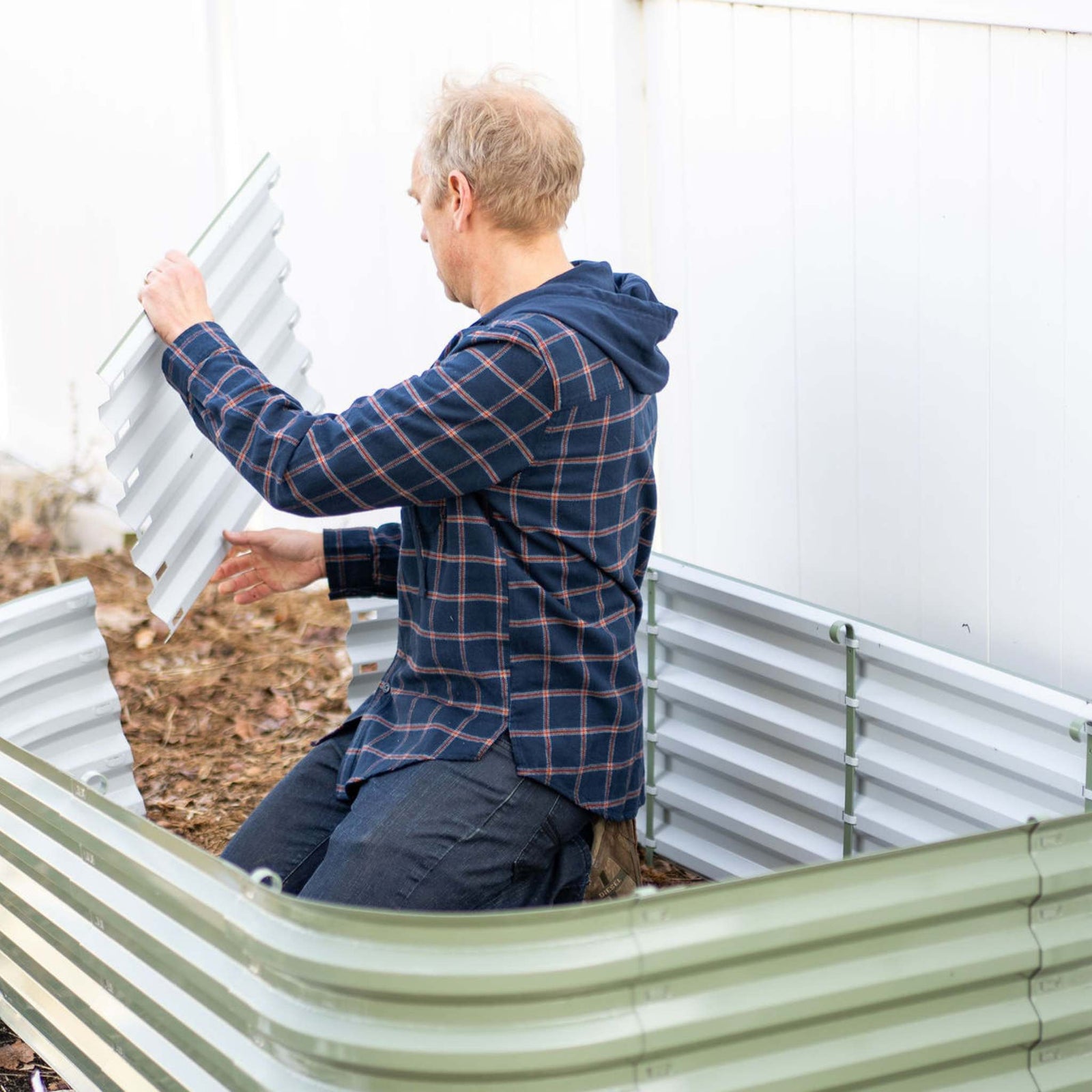 Gardener installing panels to complete the raised bed kit with no tools