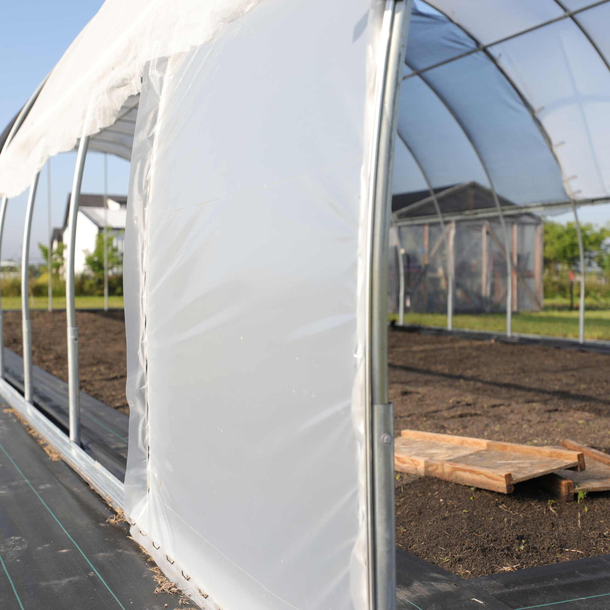 Installed wind panel on a hoop house for heat loss and wind protection