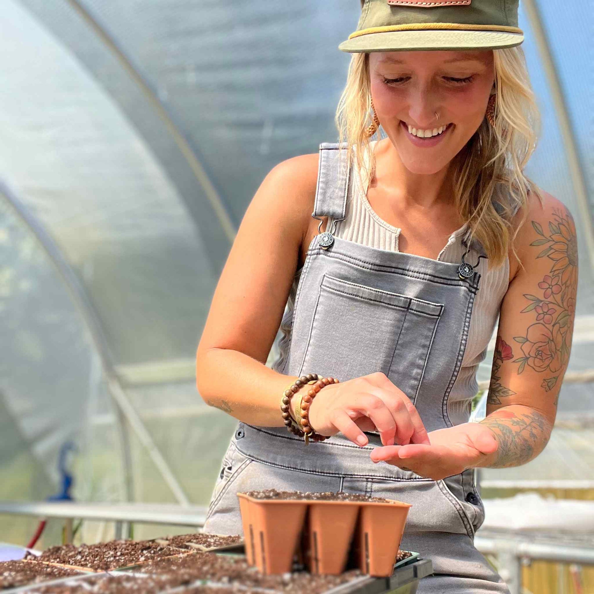 Jill of Whispering Willow Farm holding seeds and planting into bronze 6 cell in her greenhouse