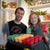 Woman holding a red and a green 3.3 inch pot. She is standing next to a man wearing a Pepper Geek shirt and holding a grey 1020 full of 3 inch pots.