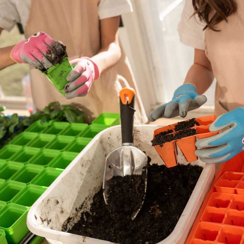 Boy adding soil to green seed starting cup, while girl adds soil to orange 6 cell seed starting plug tray