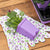 2.5 Purple Seed Starting Pot planted with pansies laying on a garden glove next to a tray of purple pots