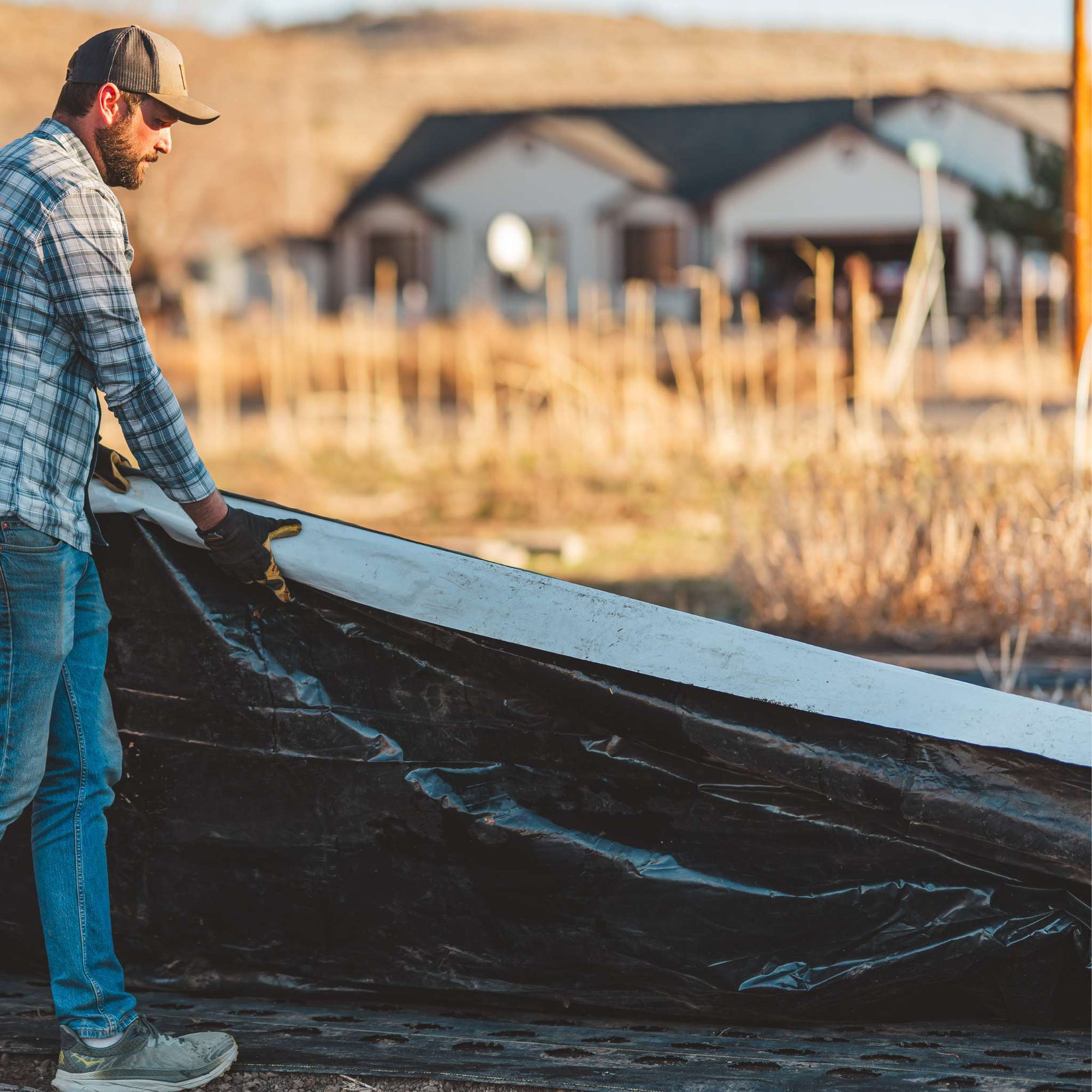 flower farmer laying silage tarp flat showing white and black side