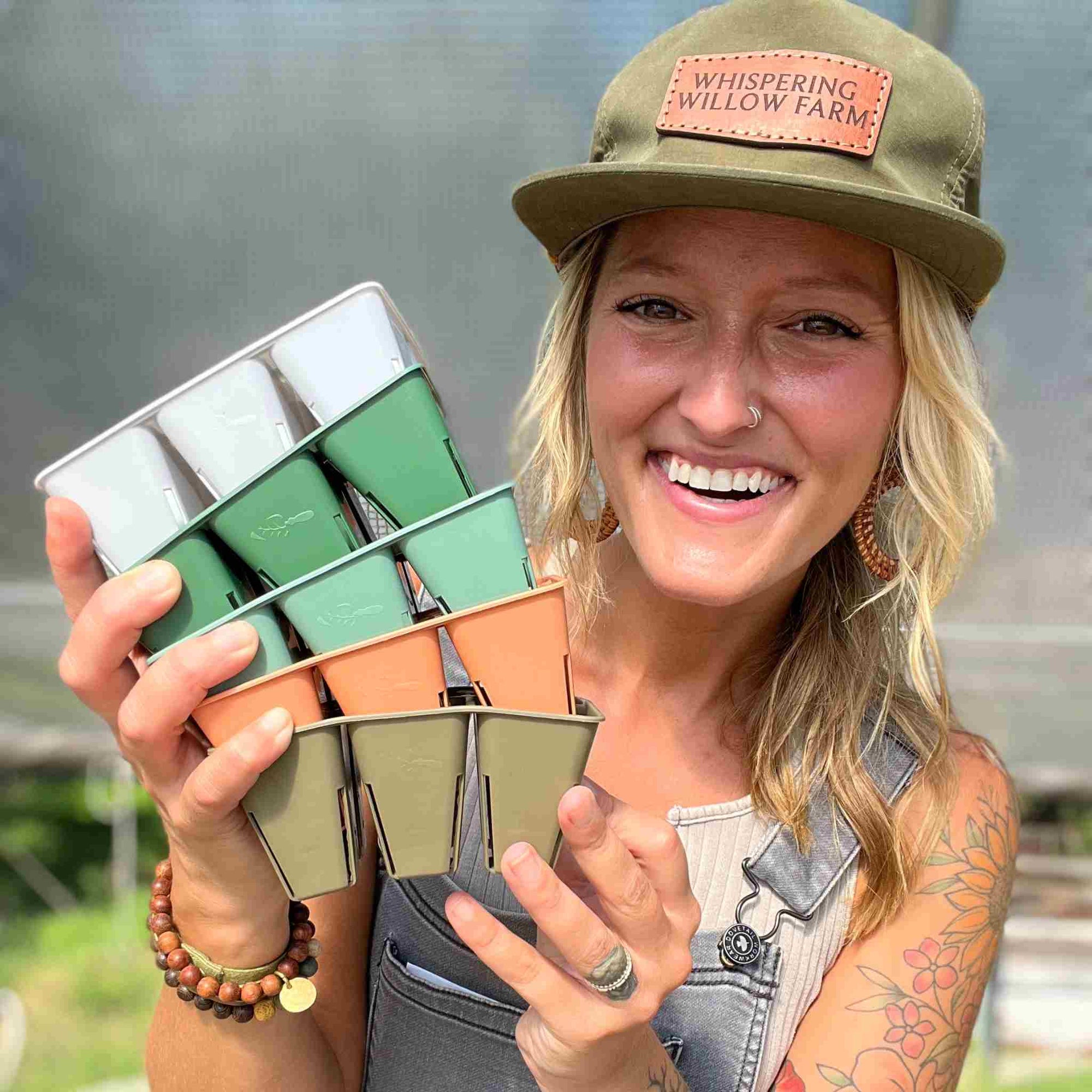 Jill Ragan holding exclusive color line of 6 cell inserts in greenhouse