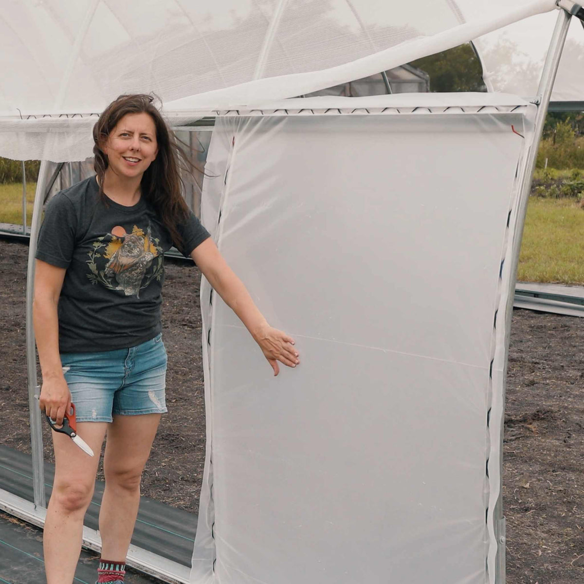 Female Farmer installing wind panel on a greenhouse to protect against wind