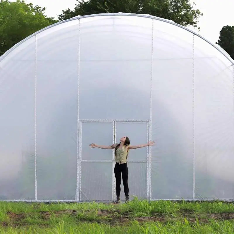Girl Standing in front of 30ft round greenhouse from Bootstrap Farmer for height reference