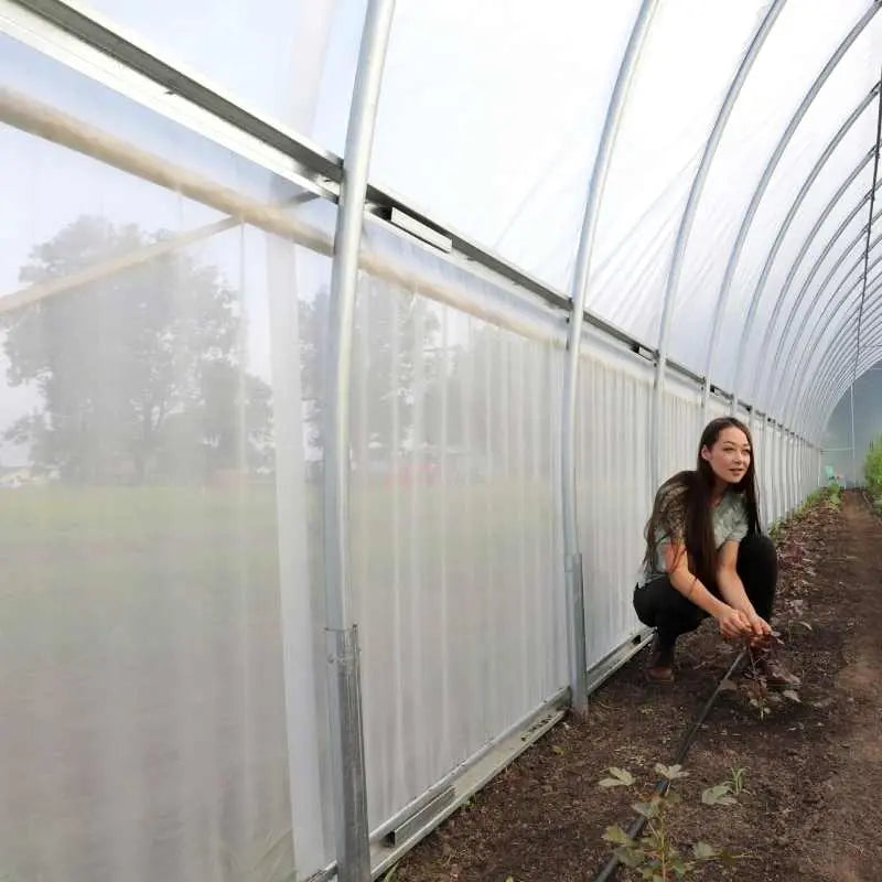 Girl learning next to 30' wide greenhouse to show reference to higher side walls